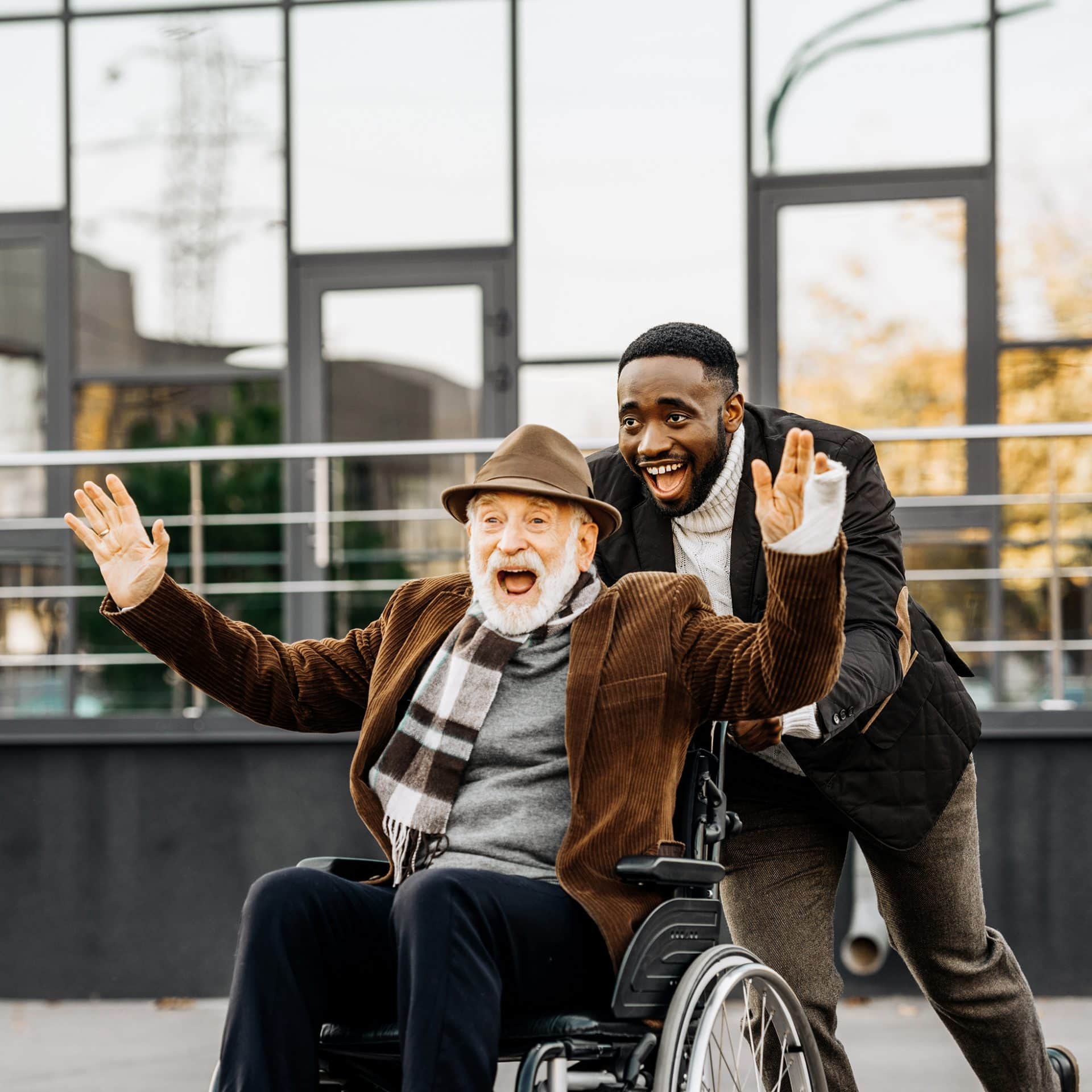 happy senior disabled man in wheelchair and african american man