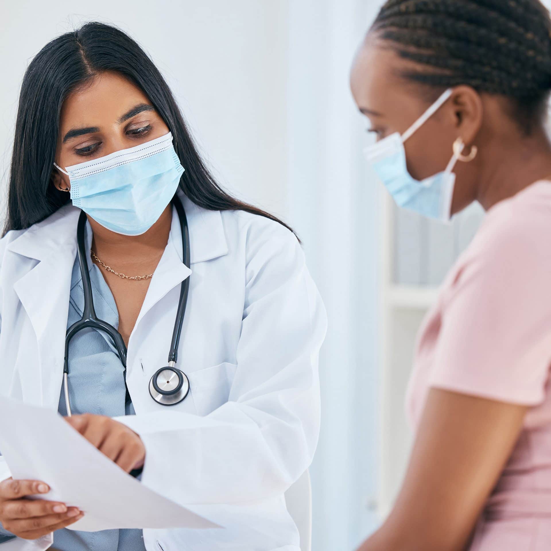 Doctor, covid mask and woman patient medical results in a health consultation in a clinic office. Diversity of women in a hospital, nurse and healthcare appointment with coronavirus consulting check