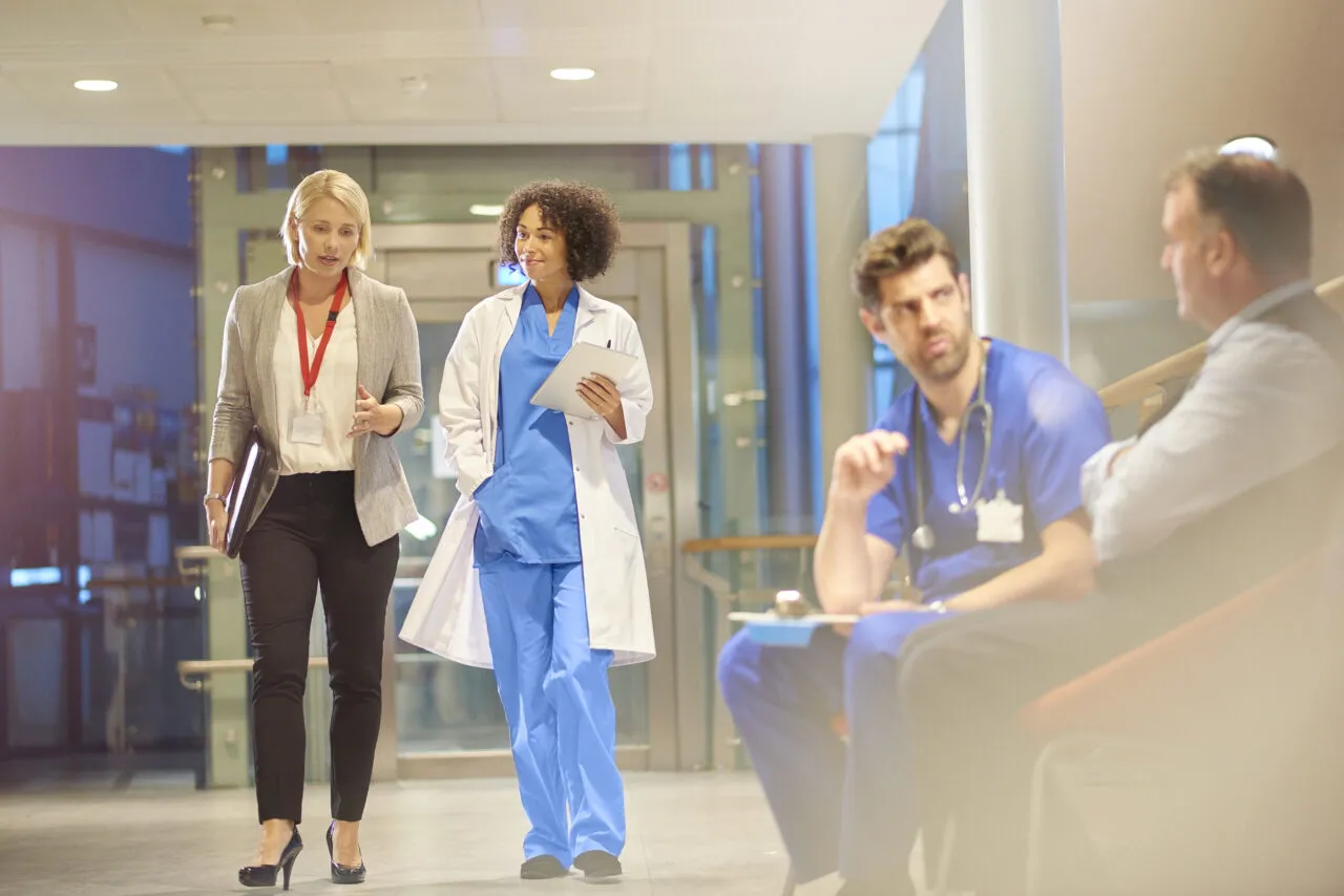 doctor listening to sales rep in hospital corridor