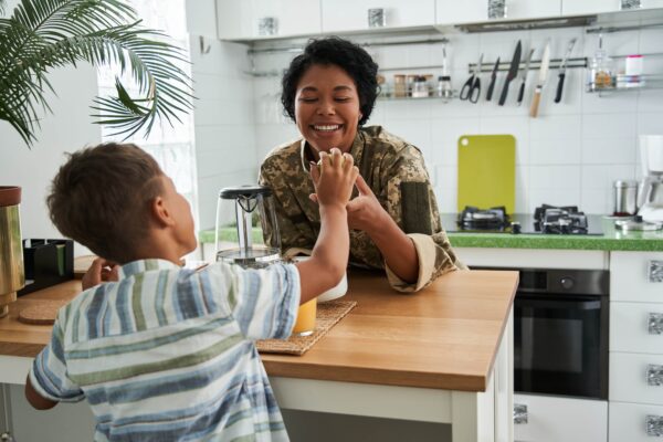 Black boy giving apple to smiling soldier mother Black boy giving apple to smiling soldier mother