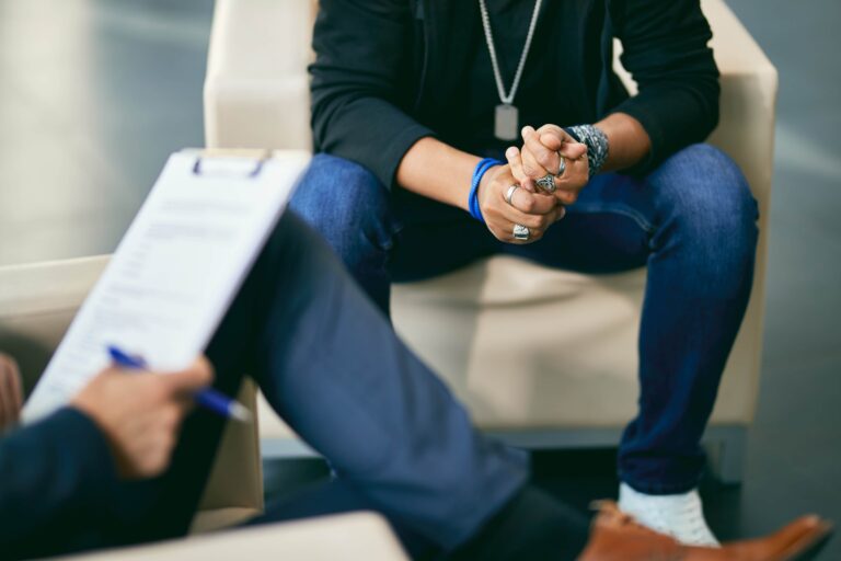 Close-up of distressed black teenage boy on counselling with psychotherapist.