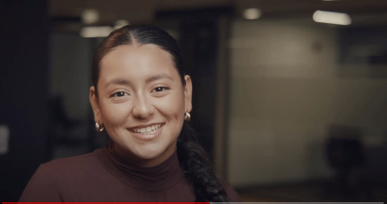 Smiling woman in professional attire in an office setting.