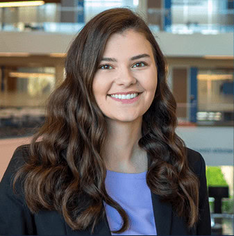 Professional woman with long brown hair smiling in office setting.