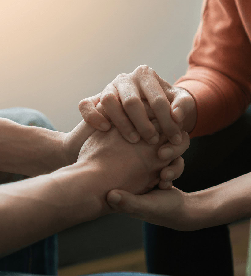 People holding hands in a supportive gesture for mental health awareness.
