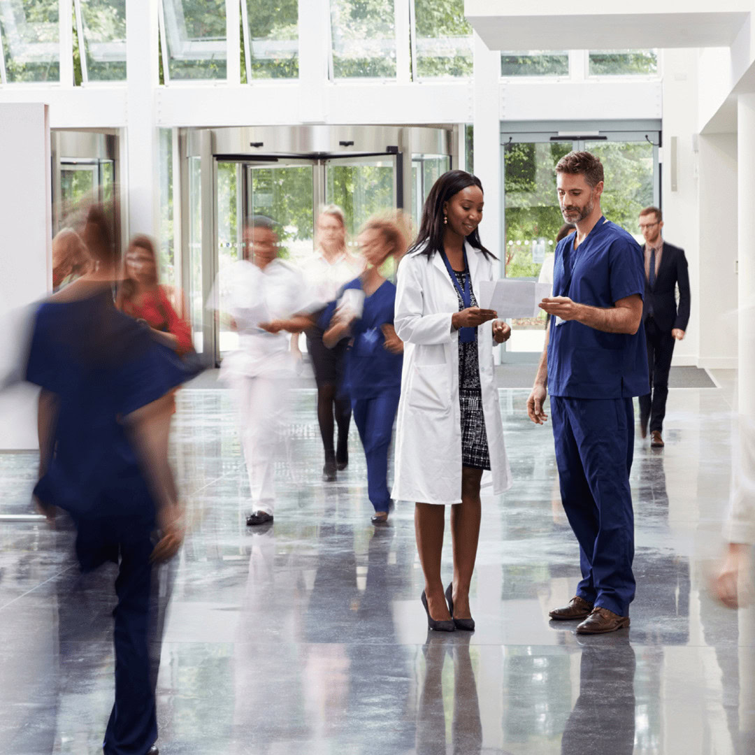 Healthcare professionals and staff in hospital lobby engaging in discussion.