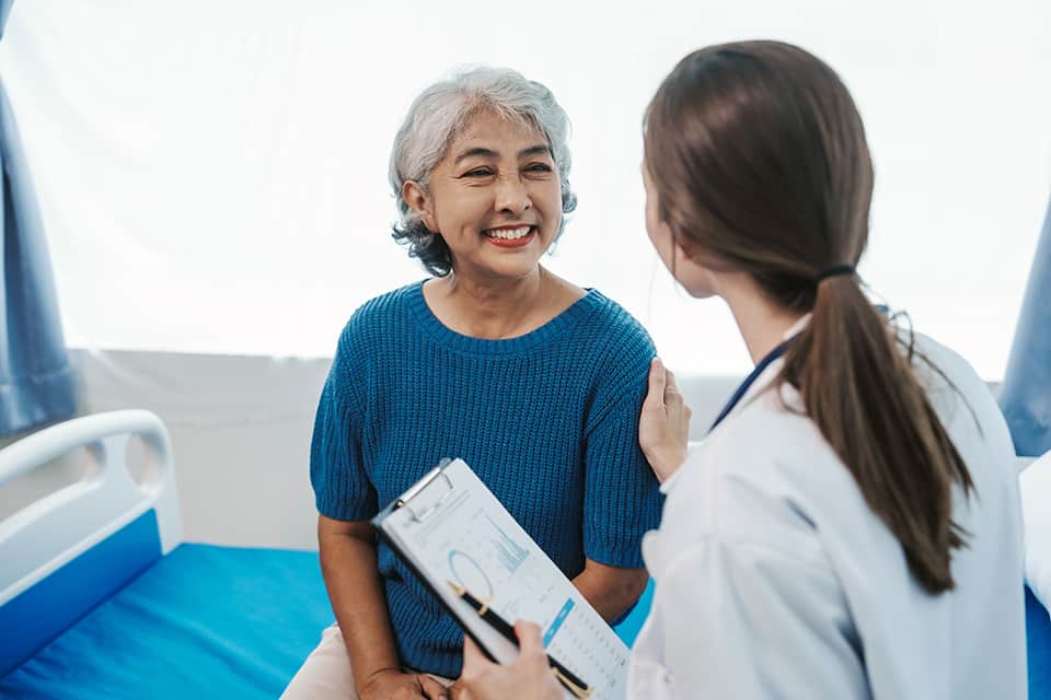 Elderly woman smiling during a medical consultation with a healthcare professional.