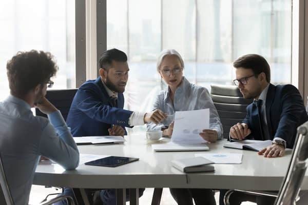 Older and young businesspeople gathered in boardroom discuss financial statistics Older and young businesspeople gathered in boardroom discuss financial statistics