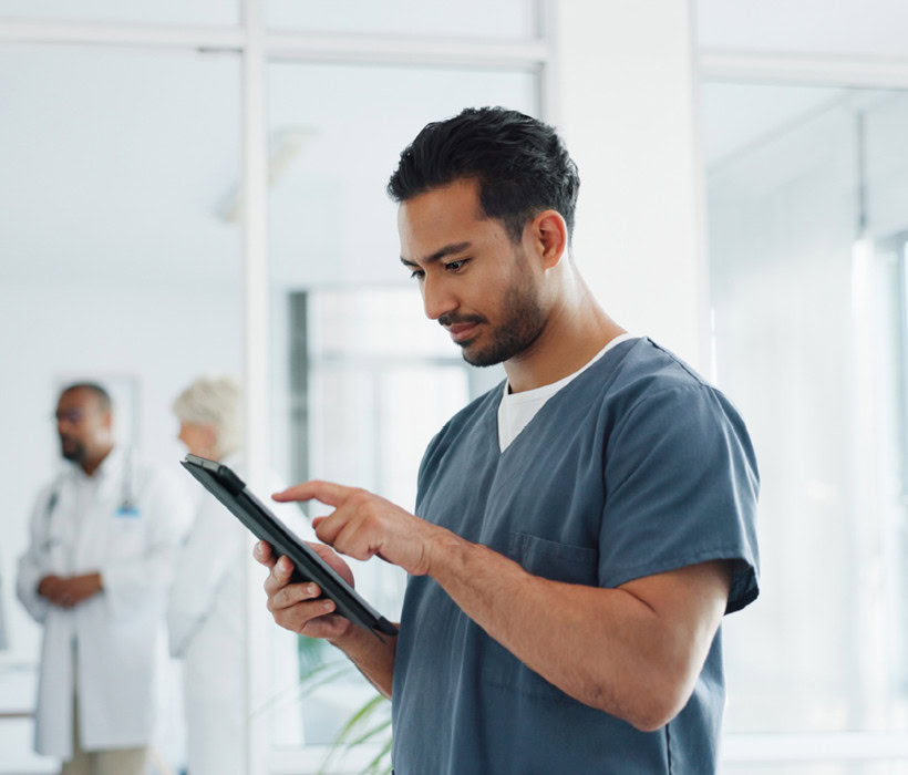 Healthcare professional using a tablet in a hospital setting.