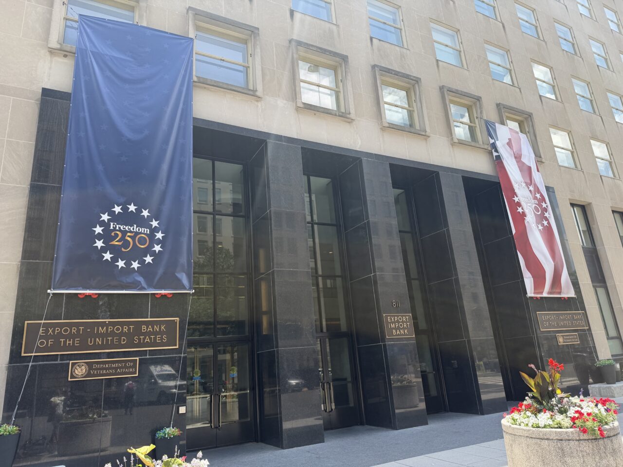 Flags and banners celebrating the US 250th Independence Anniversary outside a bank building.