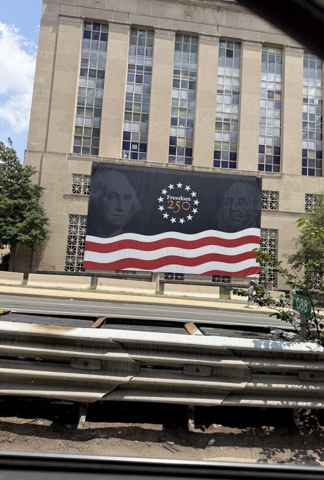 Billboard celebrating 250th Independence Day with American flag design and portraits.