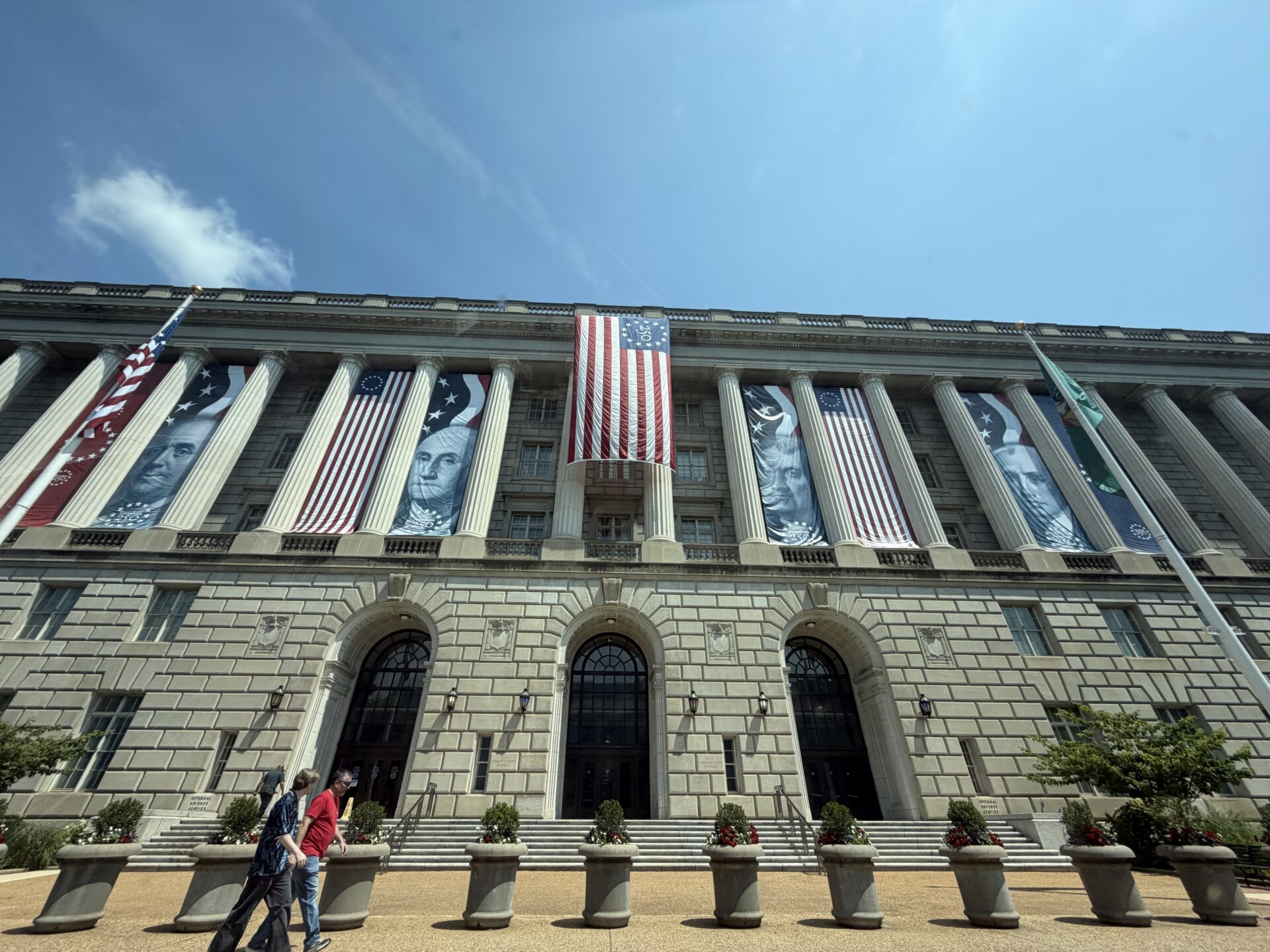 Historic building decorated with American flags and portraits for Independence Day celebration.